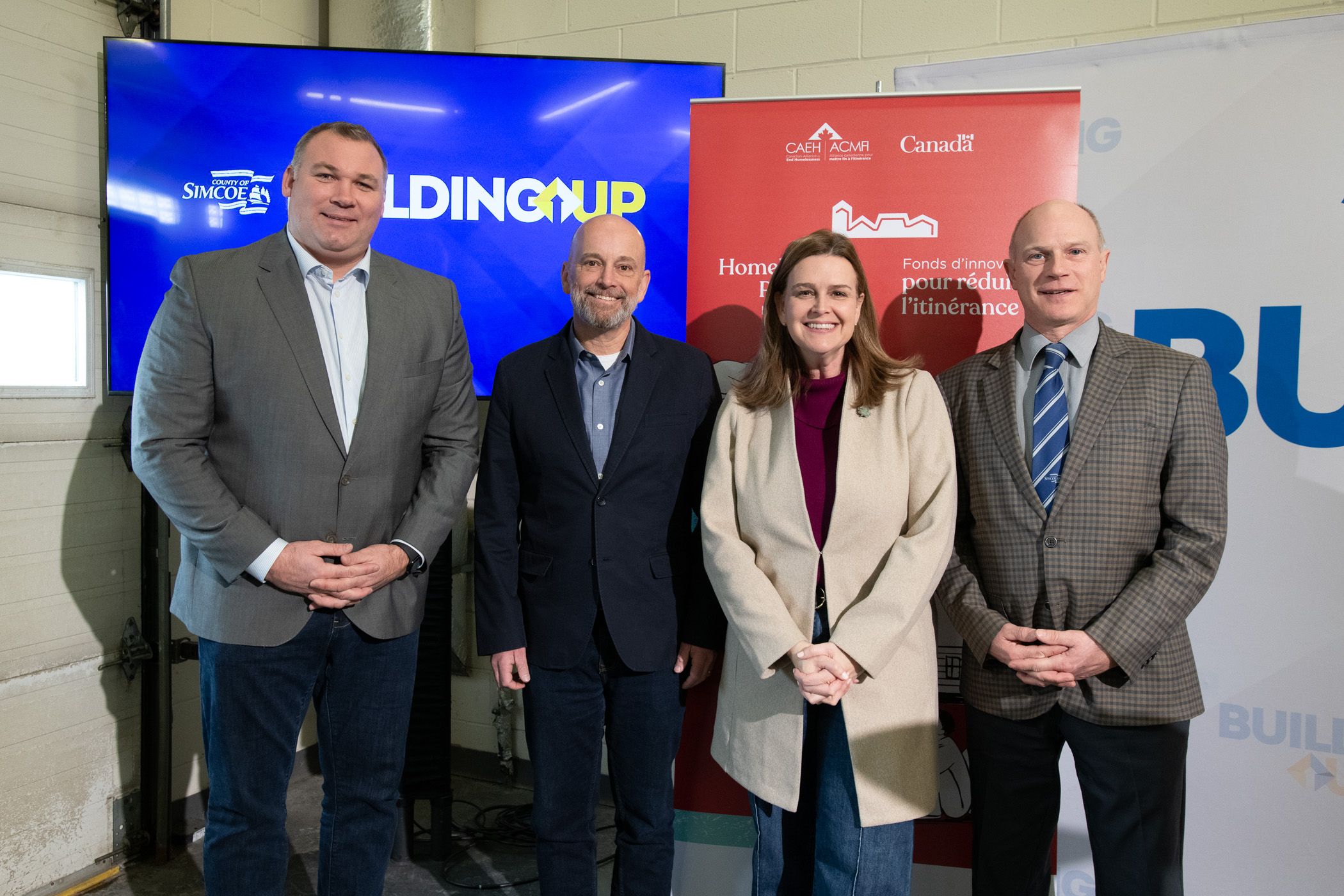 Le Maire de la Ville de Barrie Alex Nuttall, Président et directeur général de l'ACMFI Tim Richter, Federal Parliamentary Secretary to the Minister of Housing Jennifer McKelvie, and County of Simcoe Warden Basil Clarke pose for a photo at the media event announcing the new Bridge to Stability project in Barrie, Ontario.